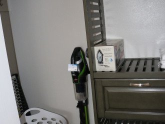closet with vacuum, iron, hamper and telescoping ladder
