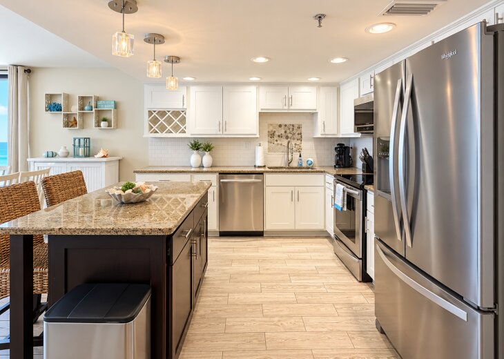 Bright coaster kitchen with granite countertops, stainless-steel appliances, a spacious island, and beautiful Gulf views.