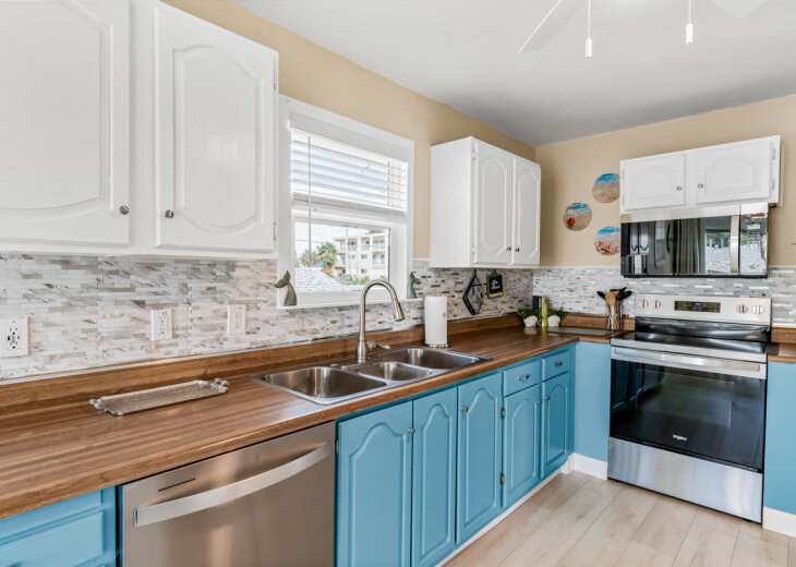 Your fully equipped kitchen features warm wood counters, turquoise cabinets, and stainless appliances perfect for home-cooked meals during your stay.