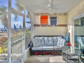 Screened patio with seating and storage for beach items.