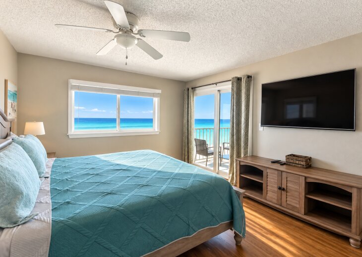 Master bedroom with a king bed, stunning Gulf views, balcony access, and a large TV.