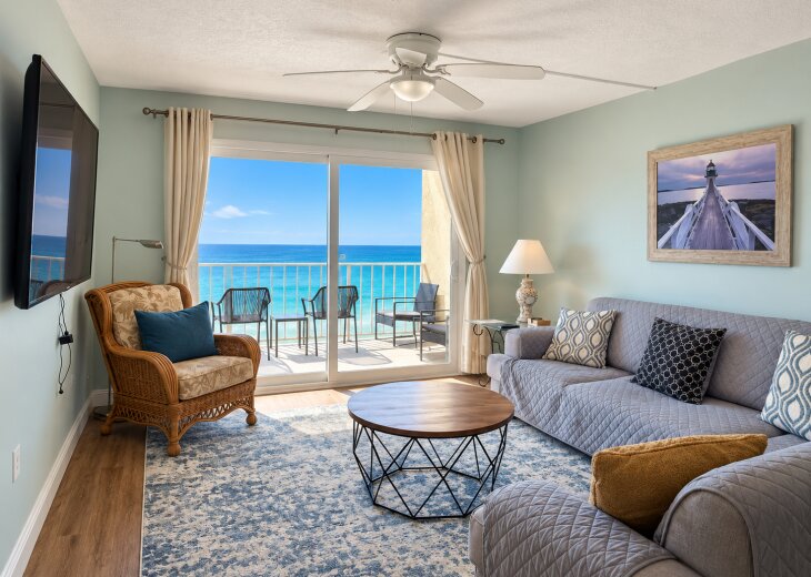 Comfortable Gulf-front living room with ample seating, a large TV, and direct balcony access.