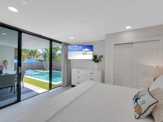 Bedroom two displays a king bed, smart TV and a glass doors to the backyard and pool.
