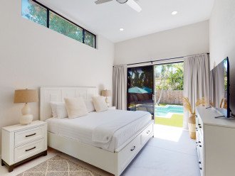 The primary bedroom boasts a king bed, smart TV, en-suite bathroom and glass doors to the backyard and pool.