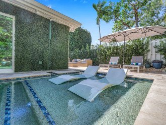 The lush garden oasis features a heated pool with its tanning shelf, two lounger areas, dining space and grill.