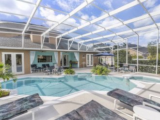 Gorgeous large tropical pool area with spa, surrounded by palm trees and shrubs.
