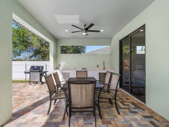The backyard patio is lighted with two ceiling fans to so you enjoy the patio any time of day. The outdoor kitchen area includes a sink, two burners, and a Weber gas grill. Patio doors pictured enter to the master bedroom.
