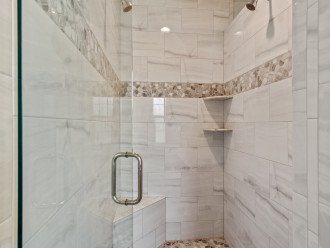 Walk-in shower in master bath with dual shower heads and a seat