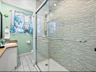 The modern walk-in shower features carefully selected tiles and dual showerhead.