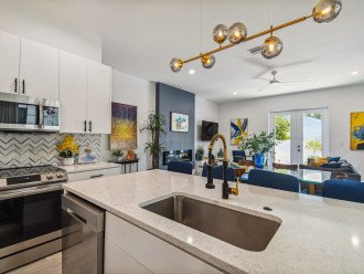 Contemporary design full kitchen, quartz countertop, contemporary barstools, tons of cabinet space, stainless steel appliances, and separate dining table with chairs.