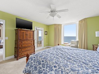 Master bedroom contains a dresser, smart TV, en suite bathroom, bay window, and door leading to balcony