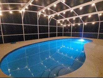 Night view of pool with patio lights