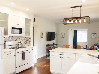 Kitchen with stove, microwave, fridge, a white porcelain farm sink and white quartz countertops.