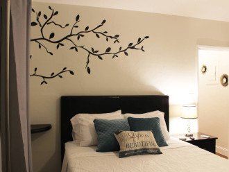 A decorative tree hangs over the bed with a side table and lamp.