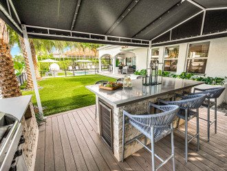 The backyard holds an outdoor kitchen equipped with bar seating for six and a grill.