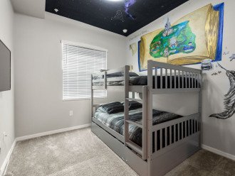 Second bedroom, with custom wall art, has a full size over full size bunk bed with a trundle beneath.