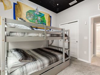 Second bedroom, with custom wall art, has a full size over full size bunk bed with a trundle beneath.