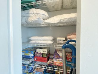 Hallway closet with pillows, baby items, 2 pack-n-plays, vacuum, games & puzzles