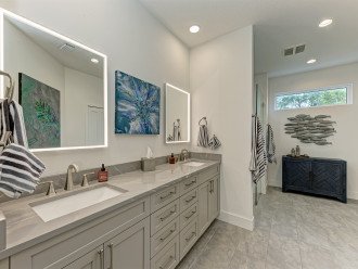 Master bathroom with dual vanity sinks and backlit mirrors