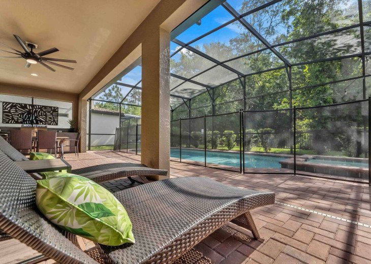 Patio with lounge chairs, table and additional chairs, grill, hot tub, pool, and sweeping views of the nature conservatory.