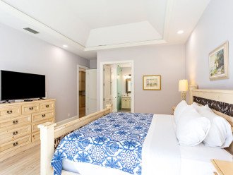 Master bedroom with king bed, tv and entrance to the pool