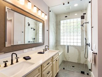 Stylish master bathroom with double vanity, zero threshold walk-in shower, large shower bench and walk-in closet