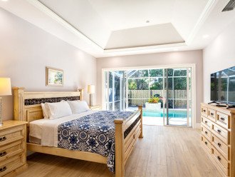 Master bedroom with king bed, tv and entrance to the pool