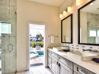Master bathroom with double vanity, walk-in shower and an entrance to the pool