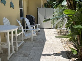 Private patio with grill and beach chairs and umbrella in storage shed.