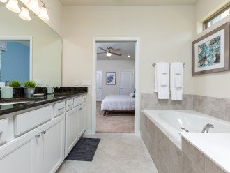 En suite master bathroom with walk-in shower and separate bathtub with private access to the pool area