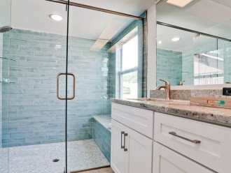 The primary bathroom features a large walk-in tile shower with a bench and double sinks. Complementary toiletries are provided.
