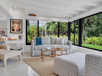 The sunroom is the perfect setting to unwind with calming views of the lush garden and pool.