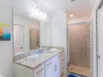 Master bathroom with walk in shower, sink with mirror, commode and a closet