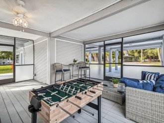 Chill out in a screened-in game room w/ ceiling fan, bar table, patio furniture.
