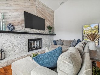 Great room, stone hearth, sofa, accent shiplap, maritime style & decor, 75” TV