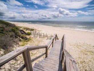 Step out onto the deck and follow the path to the sandy beach, where the ocean awaits.
