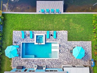 An aerial view of the outdoor oasis, with a huge patio area, hot tub, sun loungers, outdoor dining table, BBQ, decking along the canal edge and of course the pool and hot tub - what more could you want?