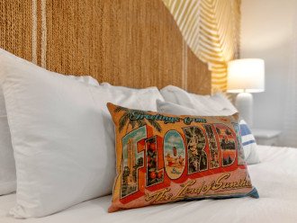 Crisp white luxury bedding and vintage Florida postcard pillow