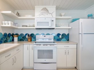 White cottage kitchen with open shelving and fully stocked.
