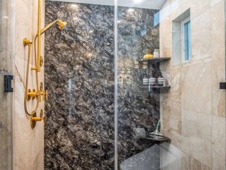 Accent wall, body sprays, and ceiling rain head shower you with luxury