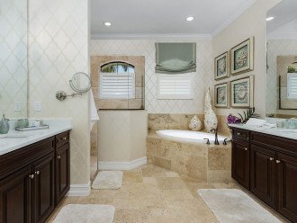 Primary bathroom with his and hers vanities, shower and bathtub