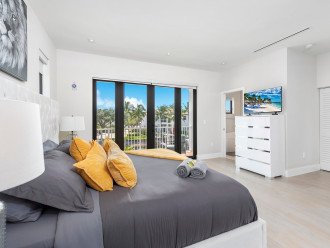 The primary bedroom features a king size bed, smart TV, ensuite bathroom and balcony access with waterfront views.