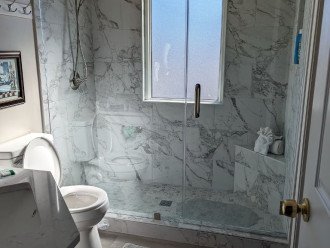 Bathroom #2 has floor to ceiling tile and glass door.