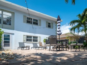 Charming shared east side yard is furnished with lounge chairs, outdoor furniture, a dining table & BBQ grill