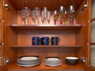 Kitchen cabinets include a variety of wine glasses, coffee mugs and dishes