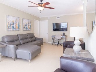 View of the fully furnished living room from the front door. Includes leather furniture & 55" smart HDTV.