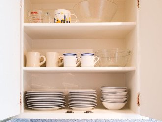 Fully stocked kitchen includes plenty of dishes, bowls and mugs