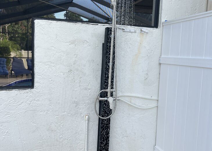 Outdoor shower beside screened patio—perfect for post-swim rinses