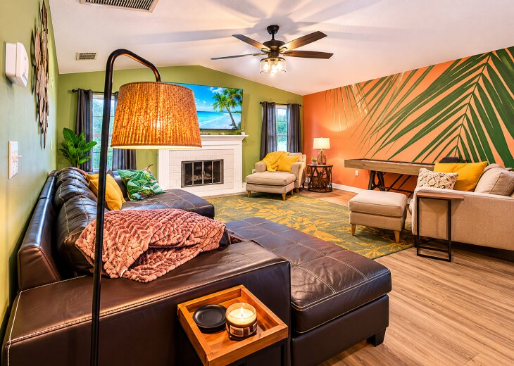 Tropical-inspired lounge with fireplace, big sectional, and game table
