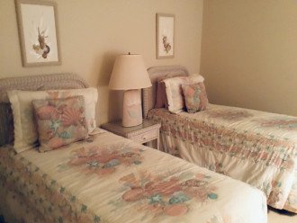 The guest bedroom features twin beds and coastal wicker furnishings.